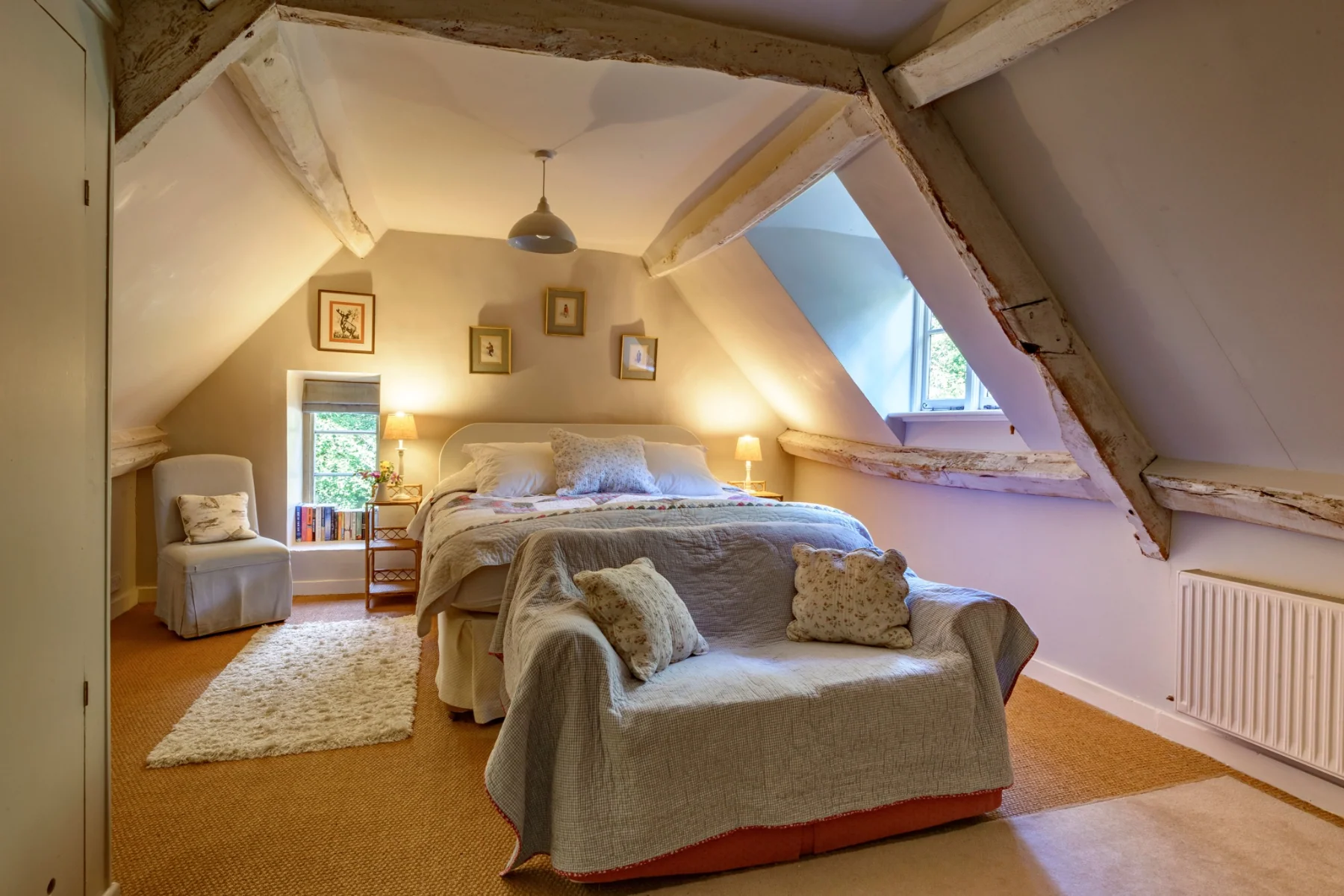 Second guest bedroom with a king-size bed and a small sofa beneath timber beams
