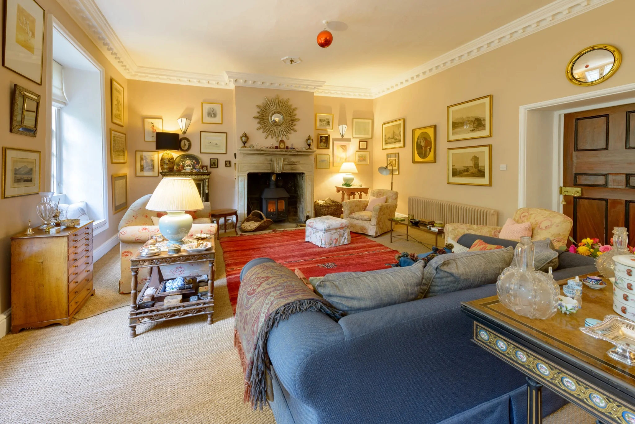 The drawing room with comfortable sofas and a lit stove in the fireplace