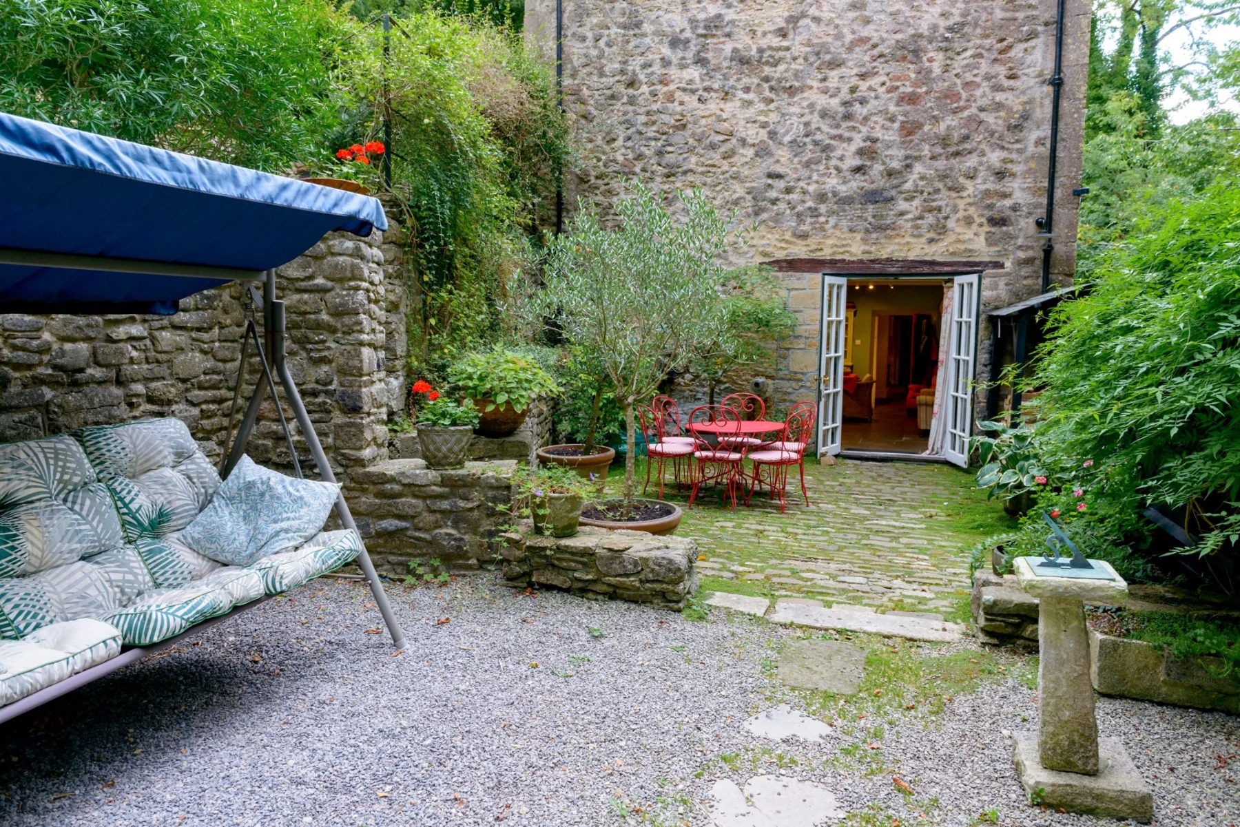 Wider view of the courtyard, with the house, planting and old stone walls